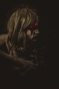 Güçlü, yüz, uzun saç metal kılıç ve savaş boya ile vahşi savaşçı