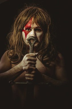 Kabile, yüz, uzun saç metal kılıç ve savaş boya ile vahşi savaşçı