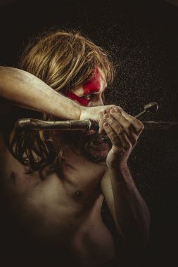 Yüz, uzun saç metal kılıç ve savaş boya ile vahşi savaşçı