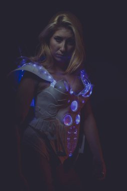 sarışın kadın beyaz gelecekteki giyen lateks takım elbise ve koyu arka plan mavi led ışıkları