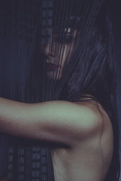 官能的な表情を持つ黒と薄いスレッドのカーテンの後ろに裸のブルネットの女性 — ストック写真