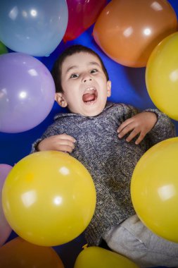 Esmer çocuk renkli balonlar ile oynamaya gülümseme ve doğum günü partisinde sevinç
