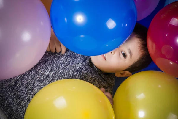 笑顔し 誕生日パーティーで喜びをカラフルな風船で遊ぶブルネットの少年 — ストック写真