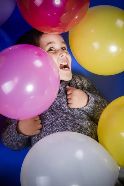 笑顔し 誕生日パーティーで喜びをカラフルな風船で遊ぶブルネットの少年 — ストック写真