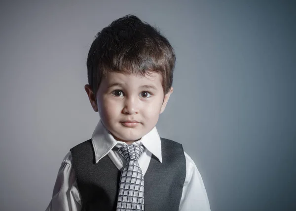 最初の雇用 小さなビジネスマン 茶色の髪の少年に身を包んだスーツし 顔と面白い表現を持つネクタイ — ストック写真