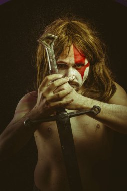 Yüz, uzun saç metal kılıç ve savaş boya ile vahşi savaşçı