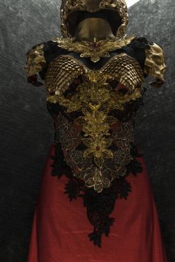 Ortaçağ, altın zırh ve metal parçalar el yapımı, ejderha derisi Gotik parçaları ve kırmızı tüyler bir kask ile bir altın zırh vardır