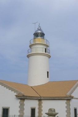 yanındaki mavi gökyüzü olmadan sakin suları ile bulutlar deniz deniz feneri. gemi kayalara varlığının uyarmak için hizmet vermektedir