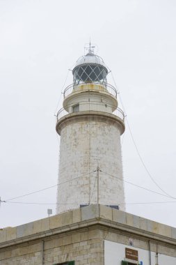 yanındaki mavi gökyüzü olmadan sakin suları ile bulutlar deniz deniz feneri. gemi kayalara varlığının uyarmak için hizmet vermektedir