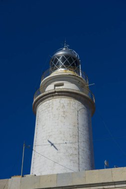 yanındaki mavi gökyüzü olmadan sakin suları ile bulutlar deniz deniz feneri. gemi kayalara varlığının uyarmak için hizmet vermektedir
