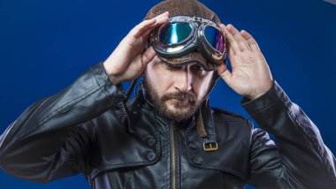 Güneş gözlüğü ve vintage havacı kask ile 20'li dişli pilot. Ceket, sakal ve anlamlı yüzler giyer deri