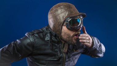 Kaza, güneş gözlüğü ve vintage havacı kask ile 20s pilot. Ceket, sakal ve anlamlı yüzler giyer deri