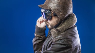20'li yaşlarda güneş gözlüğü ve vintage havacı kask ile gurur, pilot. Ceket, sakal ve anlamlı yüzler giyer deri