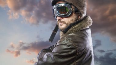 20'li yaşlarda güneş gözlüğü ve vintage havacı kask ile gurur, pilot. Ceket, sakal ve anlamlı yüzler giyer deri