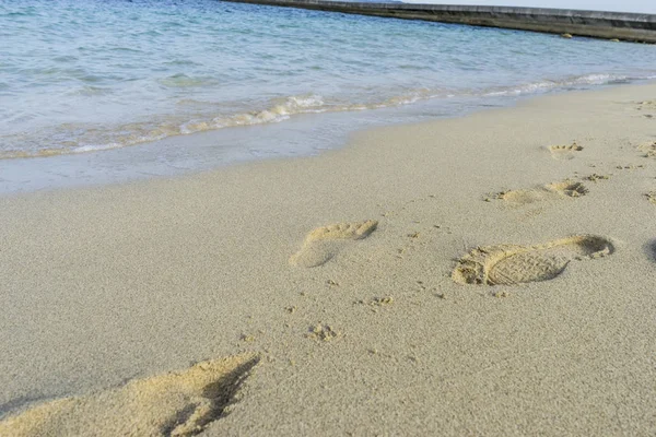 Footprints in the sand of a beach by the Mediterranean sea on the island of Ibiza in Spain, holiday and summer scene