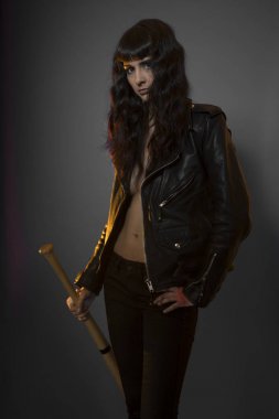 Juvenile delinquency concept, young brunette teenager with black leather jacket and jeans with a baseball bat clipart