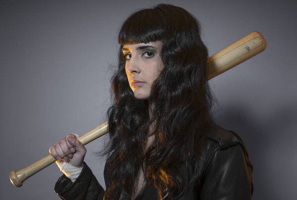 adolescence and delinquency, brunette woman in leather jacket and baseball bat with challenging aptitude