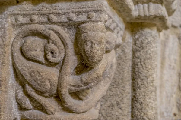 old Romanesque capital carved in the stone inside a gothic cathedral in Spain