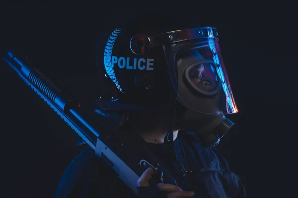 Special unit policeman in a gas mask and shield, isolated on black