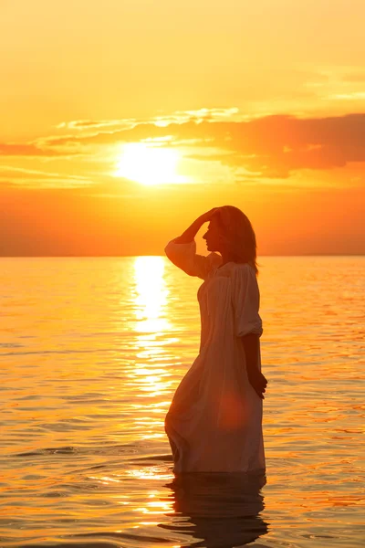 Silhueta de mulher ao pôr-do-sol. Alvorada colorida sobre o mar. Beleza natural. Mulher despreocupada desfrutando do pôr do sol na praia. Estilo de vida feliz — Fotografia de Stock