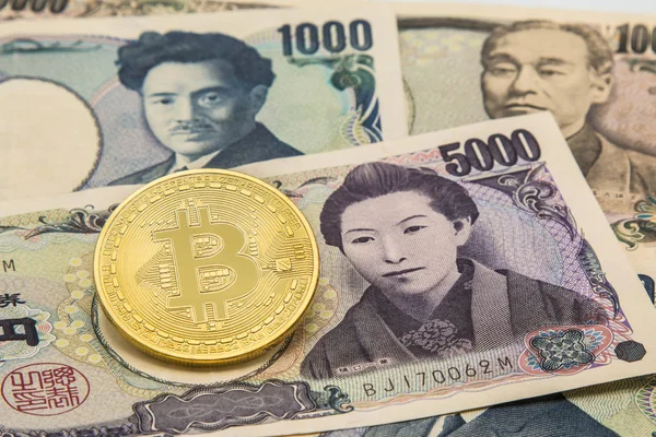 Zlatá Bitcoin na hromadu mnoha typu Japonsko bankovky pozadí. — Stock fotografie