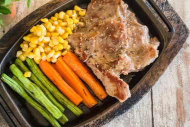 Sebze ile domuz eti biftek. Mısır, havuç, yeşil fasulye, ahşap masa