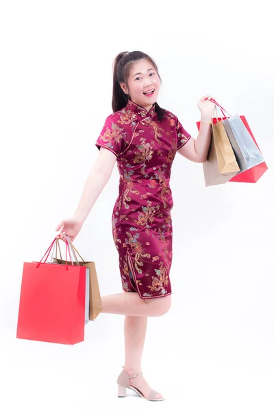 Mladá asijská žena nosí tradiční cheongsam čínských šatů s nákupní taškou a úsměv. Čínský Nový rok oslavy, silvestrovské oslavy, obchodní koncept, na bílém pozadí. — Stock fotografie