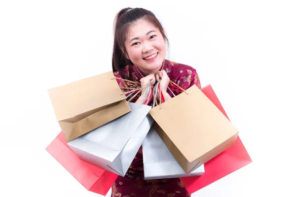 Jeune femme asiatique portant la robe chinoise cheongsam traditionnelle avec Portant un sac à provisions et sourire. Fêtes du Nouvel An chinois, Célébration du Nouvel An, Concept shopping, sur fond blanc . — Photo