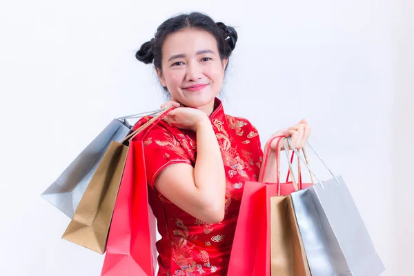 Jeune femme asiatique portant la robe chinoise cheongsam traditionnelle avec Portant un sac à provisions et sourire. Fêtes du Nouvel An chinois, Célébration du Nouvel An, Concept shopping, sur fond blanc . — Photo
