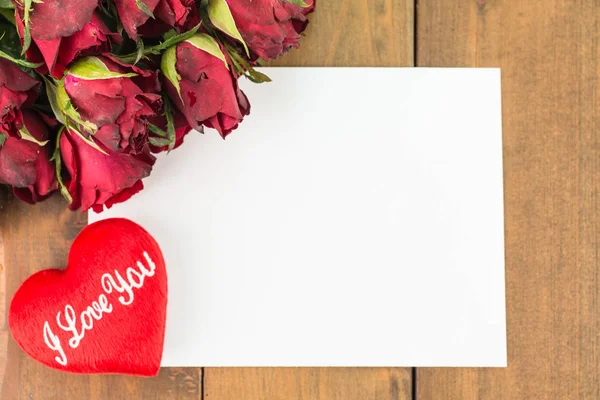 Close-up de rosas vermelhas e coração vermelho em um fundo de madeira com sinal de mensagem em branco para o seu texto ou mensagem. Cartão de saudação com rosas vermelhas e espaço para texto usando como amor, conceito dia dos namorados . — Fotografia de Stock