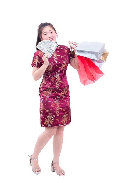 Beautiful Young asian woman wear chinese dress traditional cheongsam or qipao with Carrying a shopping bag and dollar banknote and smile. Chinese New Year Festivities, New Year Celebration. — Stock Photo, Image