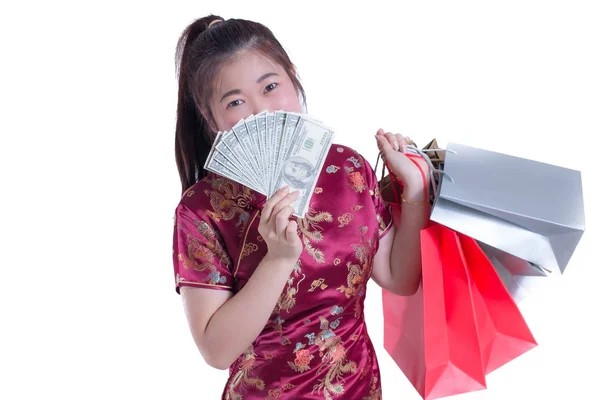 Krásná mladá asijská žena nosit čínské šaty tradiční cheongsam nebo QIPa s nákupní taškou a bankovky dolaru. Čínský Nový rok oslavy, silvestrovské oslavy. — Stock fotografie