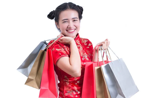 Młoda kobieta azjatyckich zużycie sukienka chińskie tradycyjne qipao lub qipao z noszenia torby na zakupy i uśmiech. Chiński Nowy Rok uroczystości, obchody nowego roku, izolowana na białym tle. — Zdjęcie stockowe
