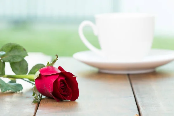 Sevimli küçük beyaz fincan kahve kırmızı gül çiçek ahşap masa ve ev bahçe arka plan ile. Romantik Tablo ayarı, Sevgililer günü kutlama, aşk kavramı, pozitif düşünme kavramı.