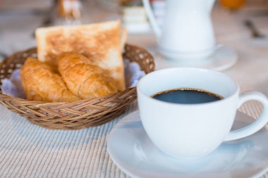 Bir fincan kahve. Kahve ve kruvasan masada bir sepet içinde Kahvaltı.