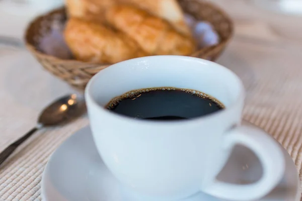 Φλιτζάνι του καφέ. Πρωινό με καφέ και κρουασάν σε ένα καλάθι στο τραπέζι. — Φωτογραφία Αρχείου
