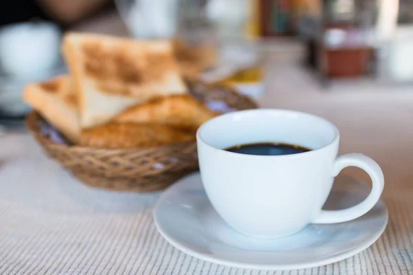 Cup of coffee. Breakfast with coffee and croissants in a basket on table.