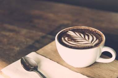 Beyaz kahve Kupası sanat kaşıkla, doku, doğrama kurulu kafede ahşap masa üzerinde. kopya alanı Vintage tarzı etkisi resimle