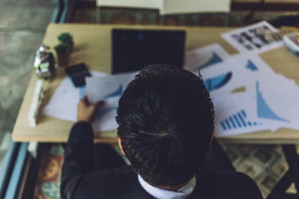 Achter ervaren van zakenman werken en financiële gegevens op Bureau met themakaarten en terwijl op leeg scherm laptopcomputer ziet werken. Papier werk, wekker en Rekenmachine op werkstation — Stockfoto