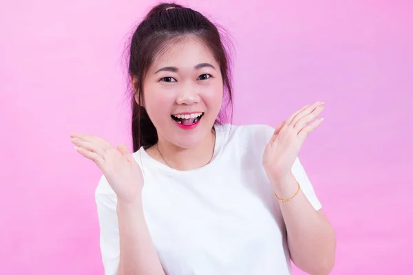 Retrato da bela jovem asiática cabelo preto usar uma camiseta branca com a mão aberta. Sentimento feliz e brilhante. Menina linda linda olhando para a câmera com sorriso adorável. isolado em fundo rosa . — Fotografia de Stock