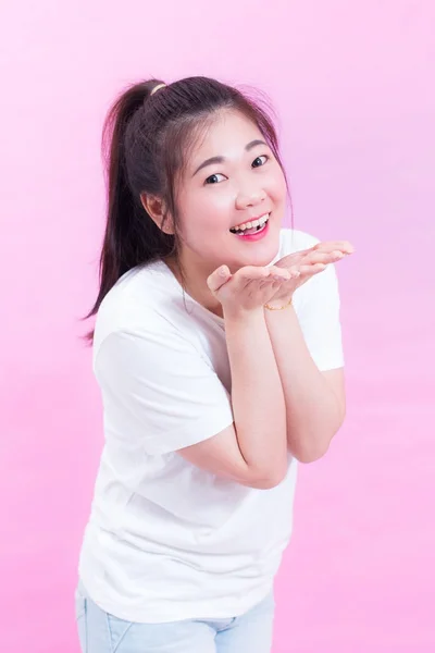 Bonito lindo de bela jovem asiática cabelo preto usar uma t-shirt branca de pé e enviar beijo sobre fundo rosa. Mulher asiática soprando beijo e olhando para a câmera . — Fotografia de Stock