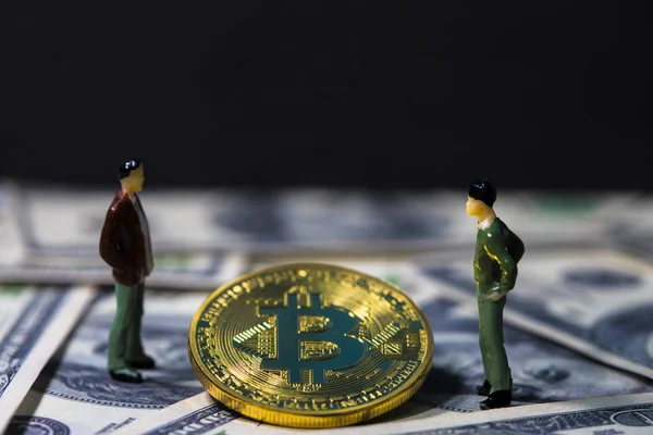Мініатюрні бізнесменів маленькі фігурки людей стоячи та поговорити про бізнес між Золотий bitcoin на сто долар банкноти. Електроніка гроші, цифрові гроші, концептуальних зображення bitcoin видобутку і торгівлі. — стокове фото