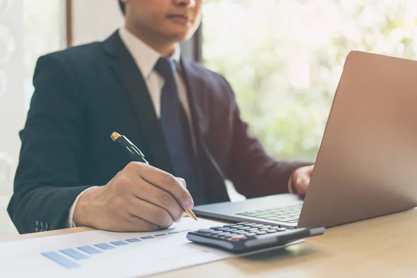 Close-up van moderne zakenman schrijven op grafiek papier in zakelijke documenten van de financiële diagram grafiek op houten tafel en het gebruik van de laptop. Zakelijk succes, verslag, groei, marketingplan, investeringen. — Stockfoto