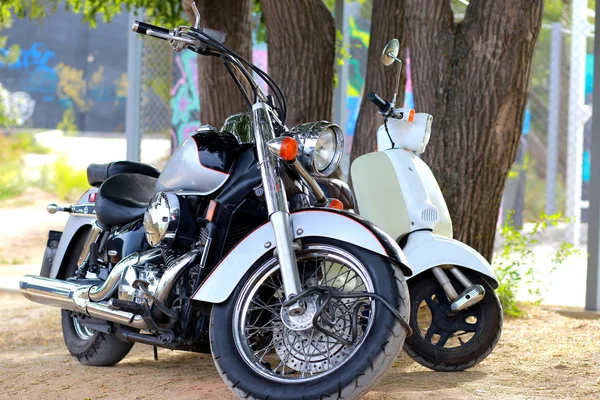 Ročník černá motocykl stojí v blízkosti bílé motorce v paprscích slunečního světla. Boční pohled — Stock fotografie