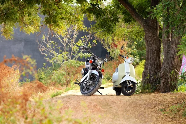 Ročník černá motocykl stojí v blízkosti bílé motorce v paprscích slunečního světla. Boční pohled — Stock fotografie