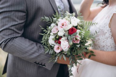 Kırmızı, pembe ve beyaz çiçekli güzel düğün buketi, güller ve okaliptüsler, şakayıklar, zambaklar