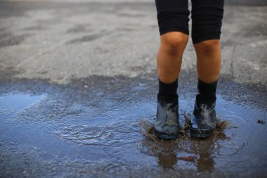 Çocuk yağmur ile atlar bir su birikintisi içine çizme.