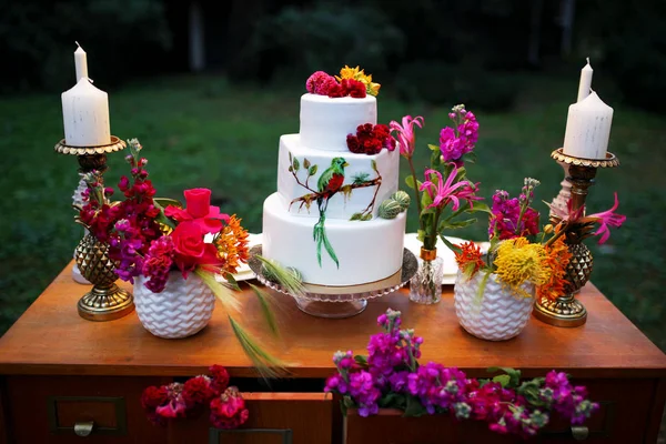 Een prachtige bruiloft drie-tiered taart versierd met vogel, roze bloemen en takken met groene bladeren in een rustieke stijl. Feestelijk dessert. huwelijksconcept. — Stockfoto