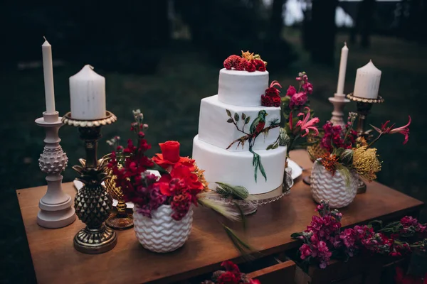 A beautiful wedding three-tiered cake decorated with bird, pink flowers and branches with green leaves in a rustic style. Festive dessert. wedding concept. — Stock Photo, Image