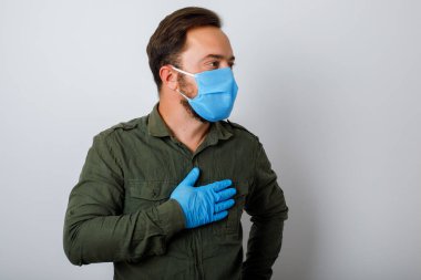 Öksürük ve ateşi olan yüz maskesi takan bir portre adam, beyaz duvar arkasında izole edilmiş. Sağlık ve tıbbi konsept